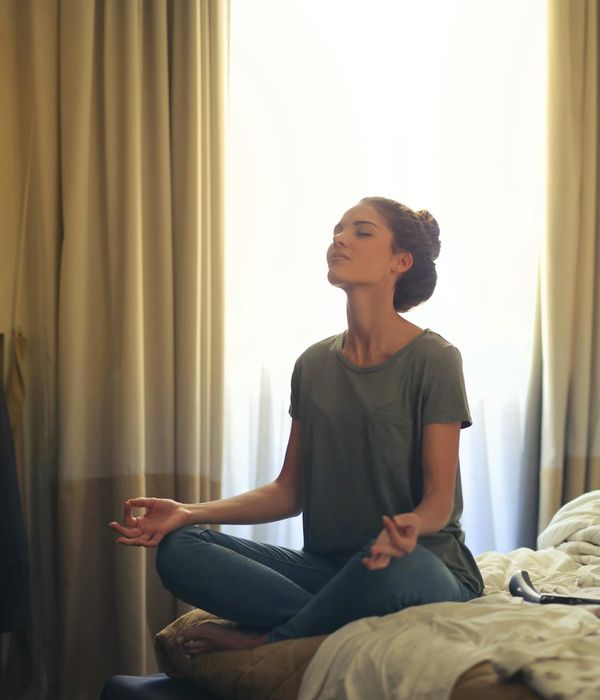 Woman in a calm breathing pose in a bright room.